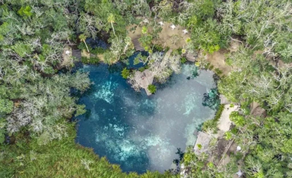 Aerial view of Cenote Corazón del Paraíso. It is heart-shaped and surrounded by vegetation.