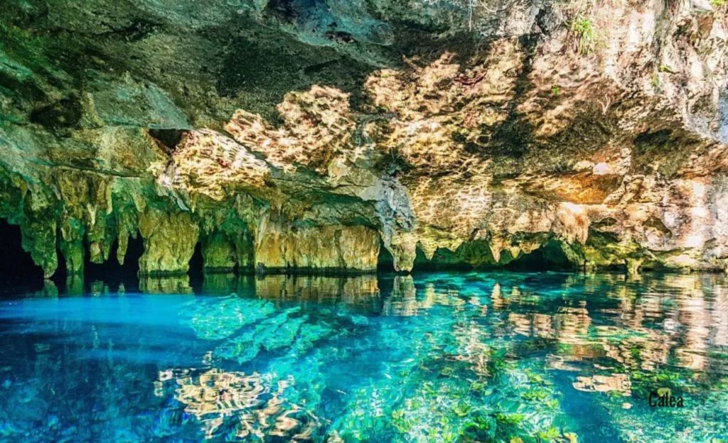 Cenote with water in various shades of blue and stalactites



