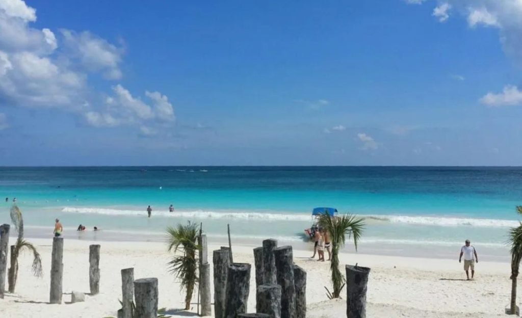 White sandy beach with locals walking in swimsuits.
