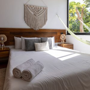 Stylish room with white, gray, and brown tones, wooden accents, a hammock, and plenty of natural light