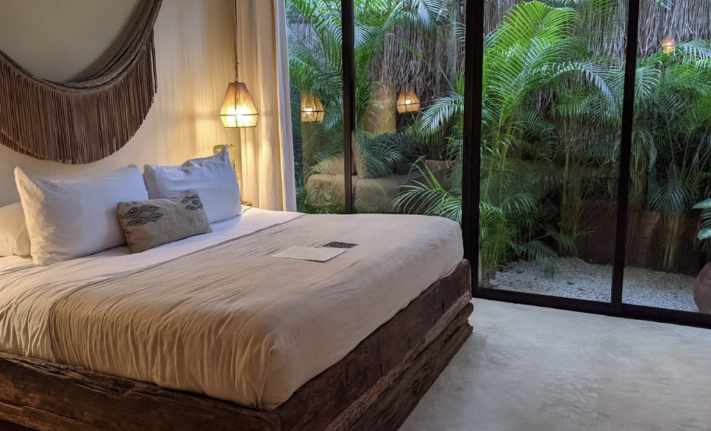 Bright white room with a balcony overlooking lush greenery.

