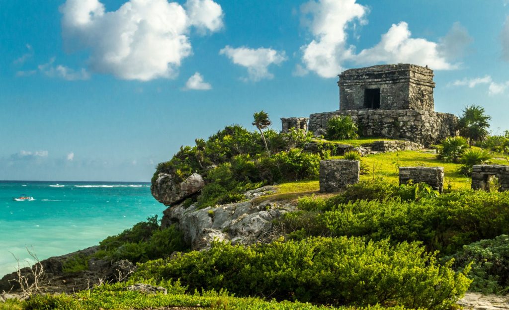 Ancient Mayan ruins overlooking a pristine beach in Tulum, with turquoise waters and lush greenery in the background. A must-see spot for travelers exploring What to do in Tulum for a Day.