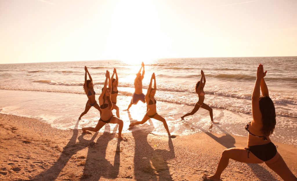 A peaceful beach in Tulum, Mexico, with people practicing yoga at sunrise, surrounded by soft sands and the calming sound of the waves.
