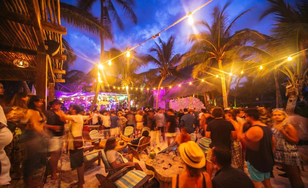 Personas atendiendo a una fiesta en la noche, en Tulum