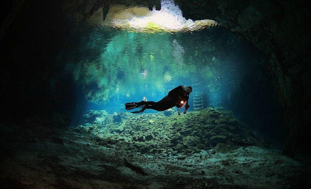 Buzo nadando en las profundidades del gran cenote