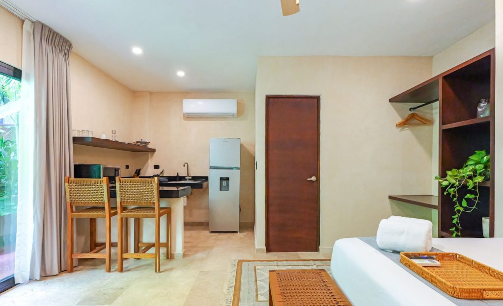 Habitación de hotel Calea, con tonos cafés, madera y una cama blanca