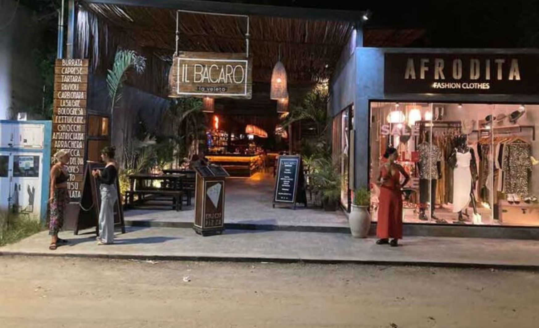 Vista del Restaurate Il Bacaro, en la noche, con algunas personas afuera