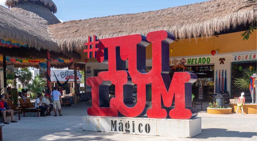 Colorful view of Tulum Centro with a large sign displaying the word "Tulum" in vibrant letters, surrounded by tourists.
