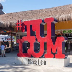 Colorful view of Tulum Centro with a large sign displaying the word "Tulum" in vibrant letters, surrounded by tourists.